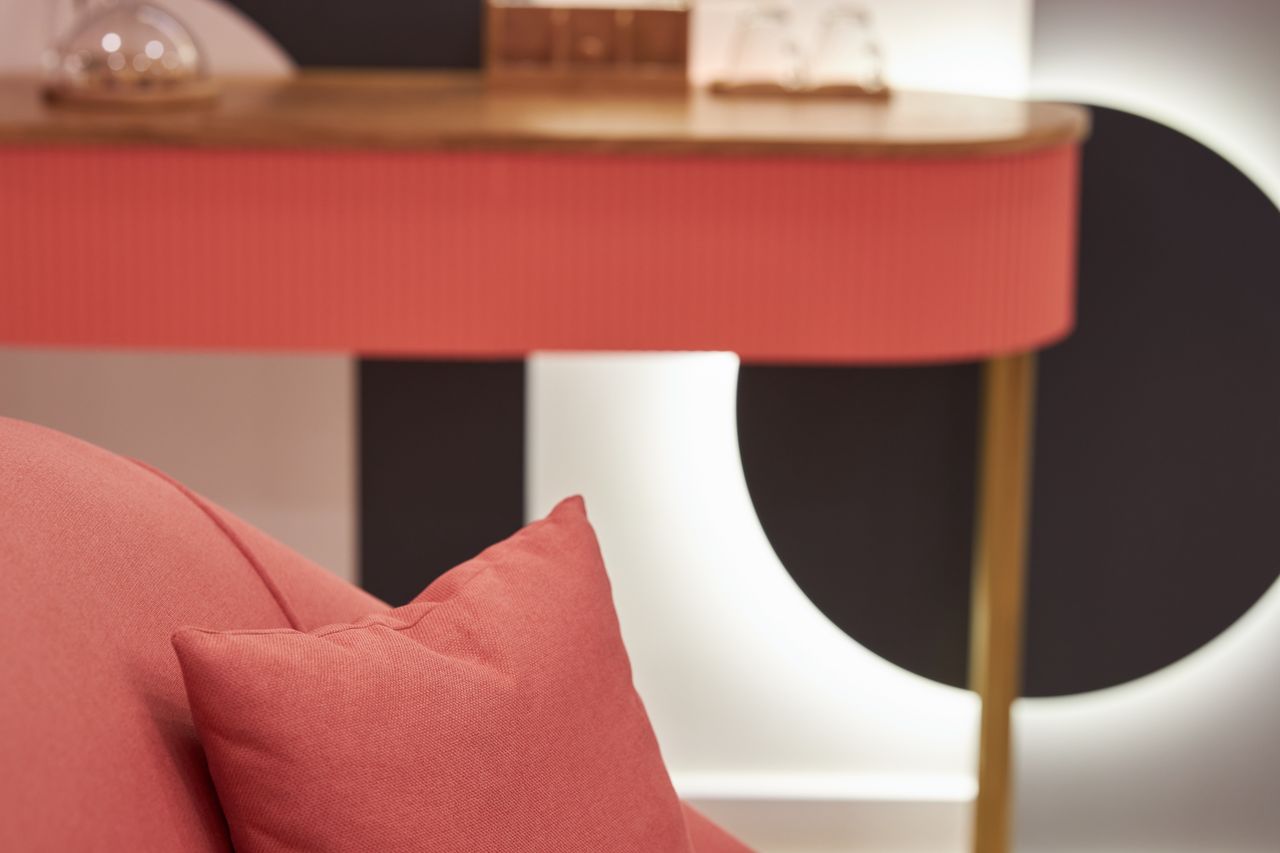 Stylish interior featuring a coral throw pillow and minimalistic decor on a wooden table.