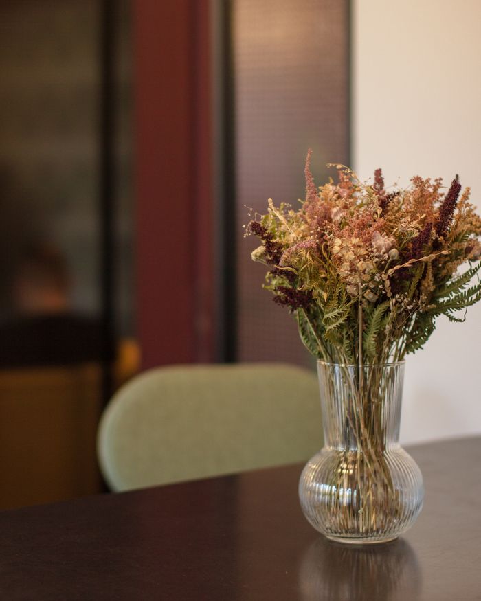 Close-up of an elegant dried flower arrangement in a glass vase on an indoor table.